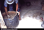 mixing clay by hand in a metal drum